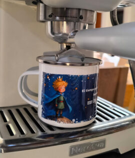Pocillo de peltre de El Principito ubicado debajo del portafiltros de una máquina de espresso blanca.